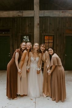 the bride and her bridesmaids pose for a photo in front of an old barn