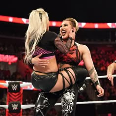 two women wrestling in a ring with one woman on her back and the other standing up