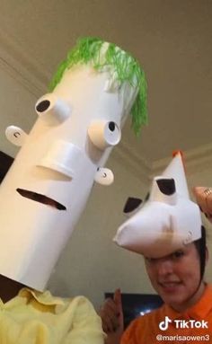 two people wearing paper hats with faces on them