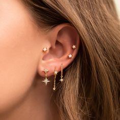 a woman wearing gold stars and chain earring with white diamonds on her ears, close up