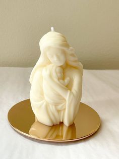 a white candle sitting on top of a gold plate