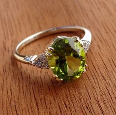 "This beautiful engagement ring is hand made in 14k yellow center and 14k white solid gold band. The natural Peridot weight is 4.02 cts and prong set in the 14k yellow gold. The Peridot measurements are 11mm x 8.9mm. The 6 side diamonds are VS-SI clarity and H color range .12cts total weight . Total gem weight is 4.14cts. We can make it any size from 5-7 and you still be able to return it within the listed time frame. Sizing outside of that range requires a resize fee if for any reason the ring Oval Peridot Gemstones For Anniversary, Anniversary Green Gemstones With Polished Finish, Round Peridot Gemstones For Anniversary, Anniversary Round Peridot Gemstones, Peridot Ring With Brilliant Cut, Classic Peridot Jewelry With Brilliant Cut, Peridot Rings, Peridot Engagement Rings, Gorgeous Rings