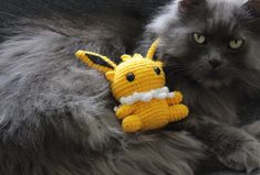 a gray cat with a knitted toy in it's lap