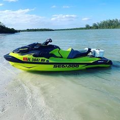 a yellow and black jet ski is in the water near some sand on a beach