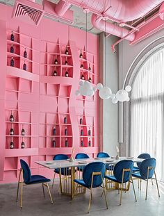 a dining room with pink walls and blue chairs