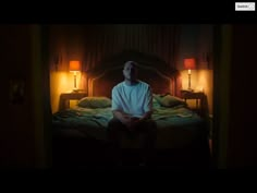 a man sitting on top of a bed in a bedroom