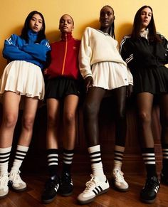 four women in short skirts and tennis shoes standing next to each other with their hands on their hipss