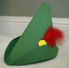 a green hat with a red feather on the top and a yellow bird on the bottom