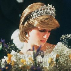 the princess is wearing a tiara and looking down at her bouquet in front of her