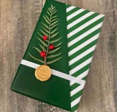 a green wrapping paper with white stripes and a gold button on it, sitting on top of a wooden table