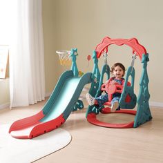 a toddler sitting on a swing set with a basketball hoop