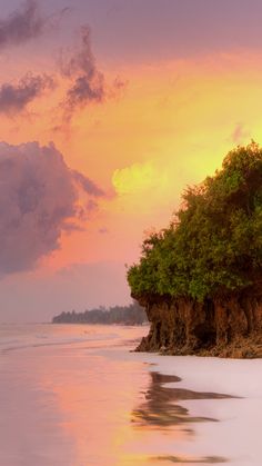 the sun is setting over an island with trees on it