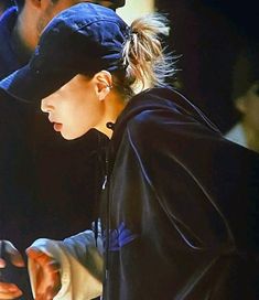 a young woman is looking at her cell phone while wearing a black hat and sweatshirt