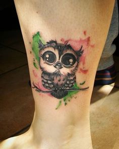 an owl tattoo on the ankle with watercolor splashes and green paint splatters