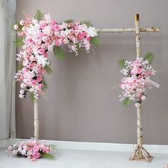 two floral arrangements are arranged on the floor in front of a gray wall with pink and white flowers