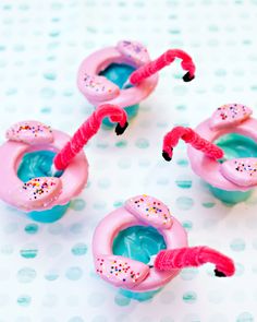 three pink flamingos with sprinkles on them sitting on a polka dot table