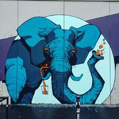 an elephant painted on the side of a building next to a wall with a beer bottle