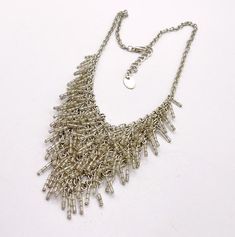 A super fun vintage bib necklace with beaded fringe. The necklace is about 15 to 17 inches long.  Silvertone metal.  Chain.  V shaped chaine maille style bib, about 4 1/2 inches wide by about 2 3/6 inches long.  Clear bugle beaded fringe for great movement.  Lobster claw clasp.  Blank hang tag!  Good vintage condition, some wear to the surface.   You can find more vintage beaded necklaces here: https://www.etsy.com/shop/OtterCatHaus/search?search_query=beaded+necklace&order=date_desc&view_type=gallery&ref=shop_search Please convo with any questions.  I combine shipping and refund overages of more than fifty cents.  Thanks for visiting today! Vintage Beads Necklace, Bib Necklaces, Bugle Beads, Beaded Fringe, Beaded Necklaces, Bib Necklace, Hang Tags, Metal Chain, V Shape