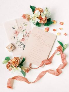 the wedding stationery is laid out with flowers