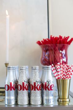 three coke bottles sitting on top of a table next to a vase