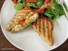 a white plate topped with a cut in half sandwich next to a salad