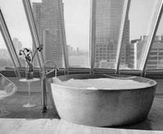 a large bathtub sitting in front of a window next to a wine glass holder