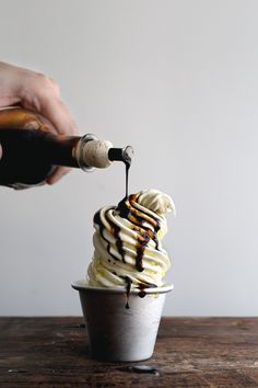 someone is pouring chocolate syrup on top of an ice cream sundae with whipped cream