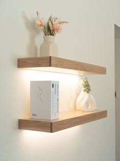 two wooden shelves with books and vases on them, one is lit up by the light