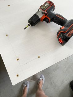 a person with their feet on the table holding a cordless drill and screwdriver