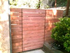 a wooden fence next to a bush and shrubbery