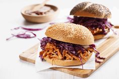 two pulled pork sandwiches sitting on top of a cutting board