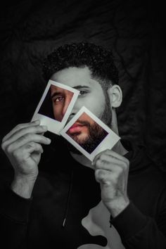 a man holding up two photos with his face in front of him and the other one behind him