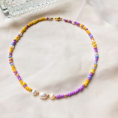 Summer Pearls necklace/ choker with purple & yellow beads This beautiful and stylish pearl choker is about 35 cm in length. To be creative and explore the versatility of the necklace, you can also wear it as a bracelet!  Made with love - Made in Berlin Freshwater pearls are also a natural product, and the shape and colour vary slightly. The pearl choker is made with jewelry gold wire. Total length: 35 cm  Seed beads: 3-4 mm, also gold-plated Diameter of freshwater pearls: 3-4 mm & 6mm  --------- Handmade Yellow Pearl Necklace For Gift, Handmade Yellow Pearl Necklaces, Yellow Pearl Beaded Necklaces As Gift, Yellow Beaded Pearl Necklace As Gift, Yellow Beaded Pearl Necklace Gift, Yellow Pearl Necklaces With Round Beads, Yellow Beaded Pearl Necklace, Purple Choker With Colorful Beads For Gift, Trendy Purple Round Bead Necklaces