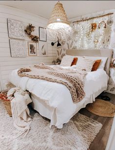 a bedroom with white bedding and lots of pictures hanging on the wall above it