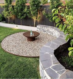 an outdoor patio with gravel and stone seating area in the center, surrounded by greenery