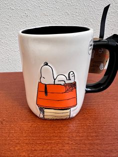 a coffee mug with snoopy on it sitting on a table