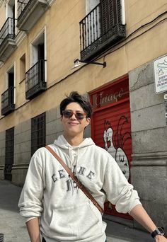 a man standing in front of a building with his hands on his hips and smiling