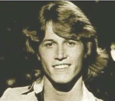 an old black and white photo of a young man with long hair smiling at the camera