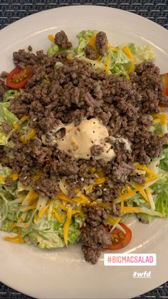 a white plate topped with meat and lettuce covered in dressing next to tomatoes