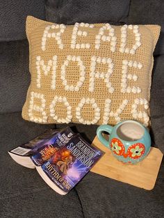 a coffee cup, book and pillow on a couch with the word hope written across it