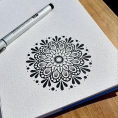 a pen sitting on top of a paper next to a drawing pad with a flower design