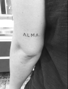 a person with a tattoo on their arm that says alma, in black and white