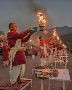 men in red and white outfits holding torches on their hands while others stand around them