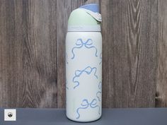 a blue and white water bottle sitting on top of a table next to a wooden wall