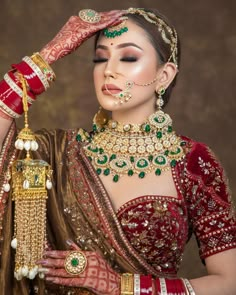 a woman in a red and gold bridal outfit with her hands on her head