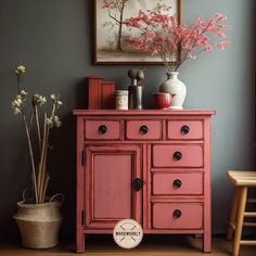 a red cabinet with flowers and vases on top