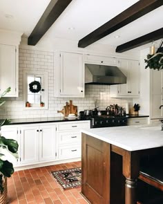 a kitchen with white cabinets and an island in front of a stove top oven next to a potted plant