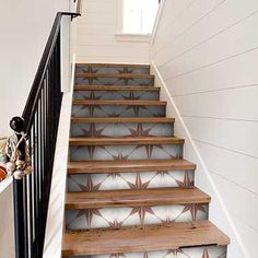 a stair case with decorative wallpaper on the bottom, and wooden handrails