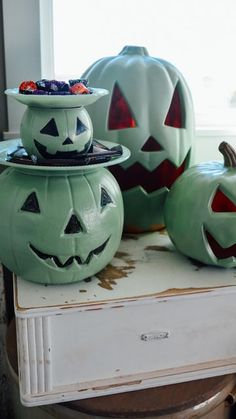 three carved pumpkins sitting on top of a white table next to a window sill