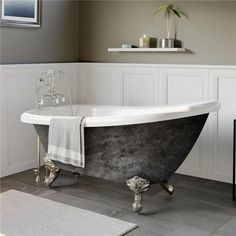 an old fashioned claw foot bathtub in a bathroom with gray walls and flooring